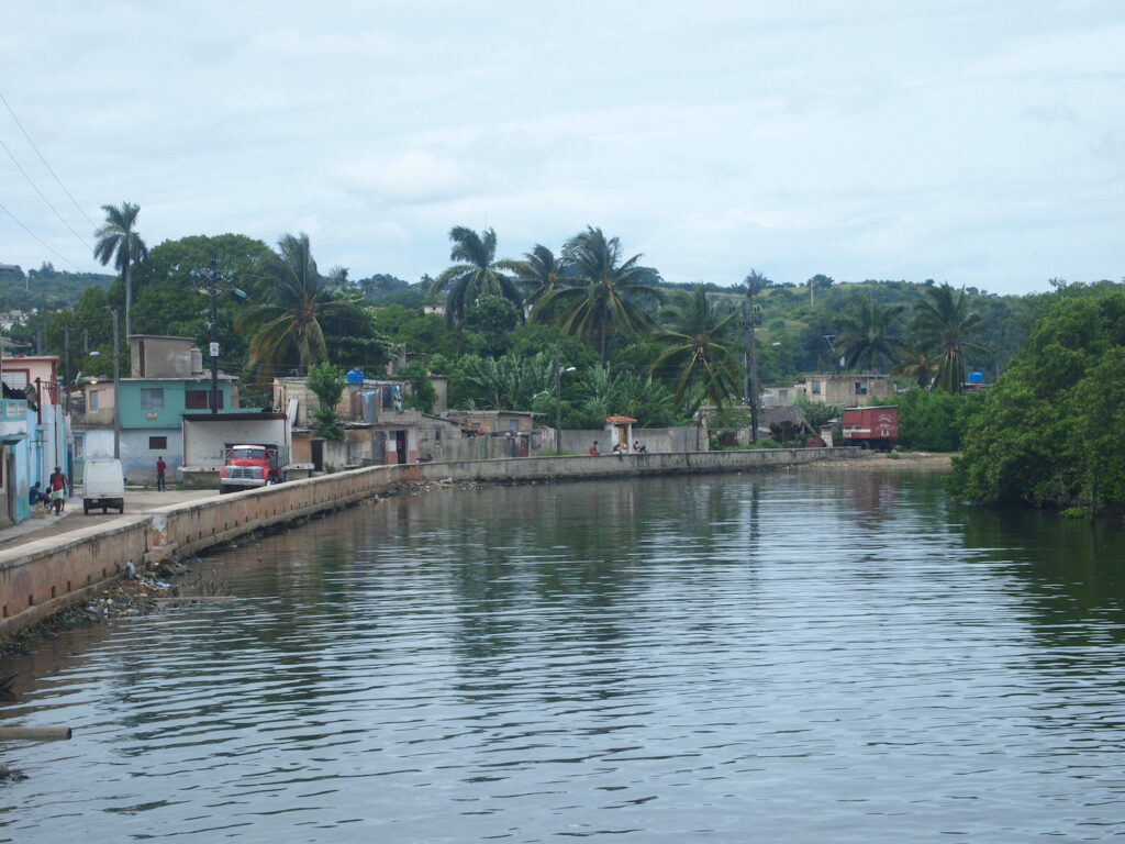 Photograph of a town and a canal with lush vegitation.