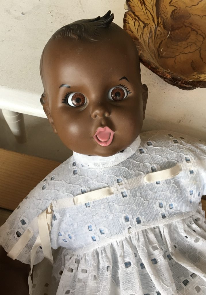 Muñeca Negra con un vestido de encaje azul, ojos grandes y boca abierta