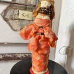 Black doll with orange dress with white pattern